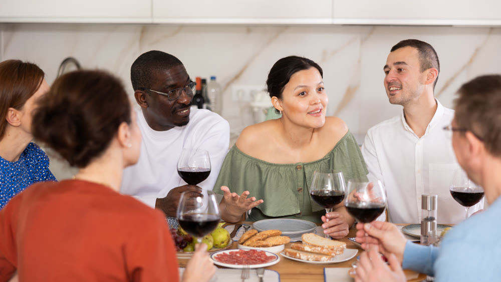Friends sharing laughter and conversation over dinner at home