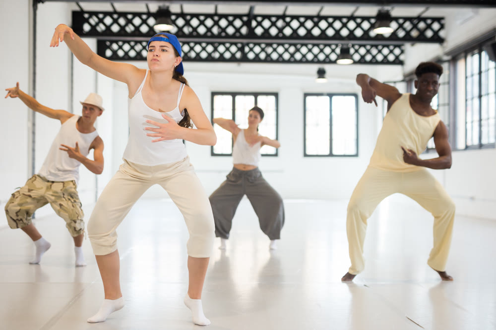 People in casual clothes training hip-hop in class, posing and having fun