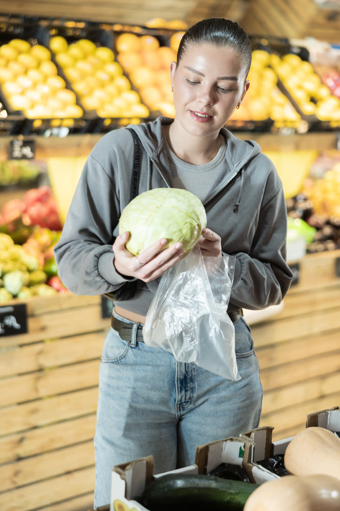 Woman buyer choosing fresh cabbage at vegetable market