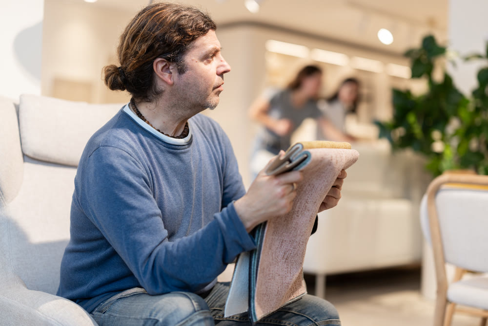 Man sitting in an armchair choosing fabric for sofa
