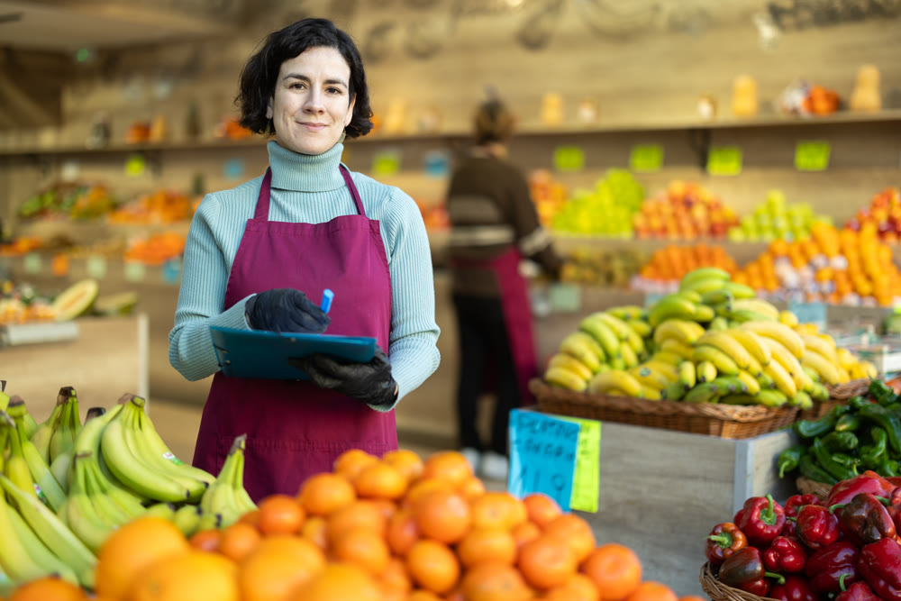 Woman store employee with folder of documents takes inventory in vegetable store
