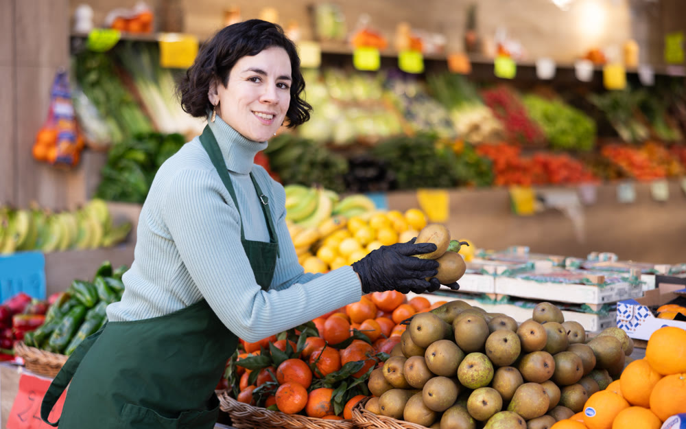 Adult woman seller puts pears on display