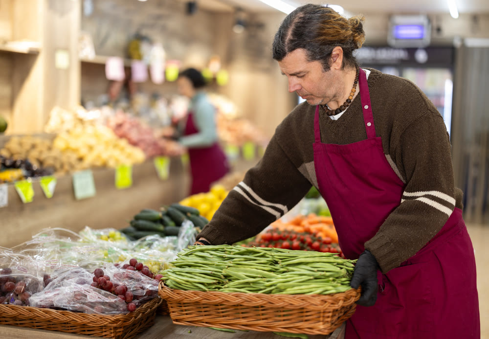 Adult man seller with basket of green peas