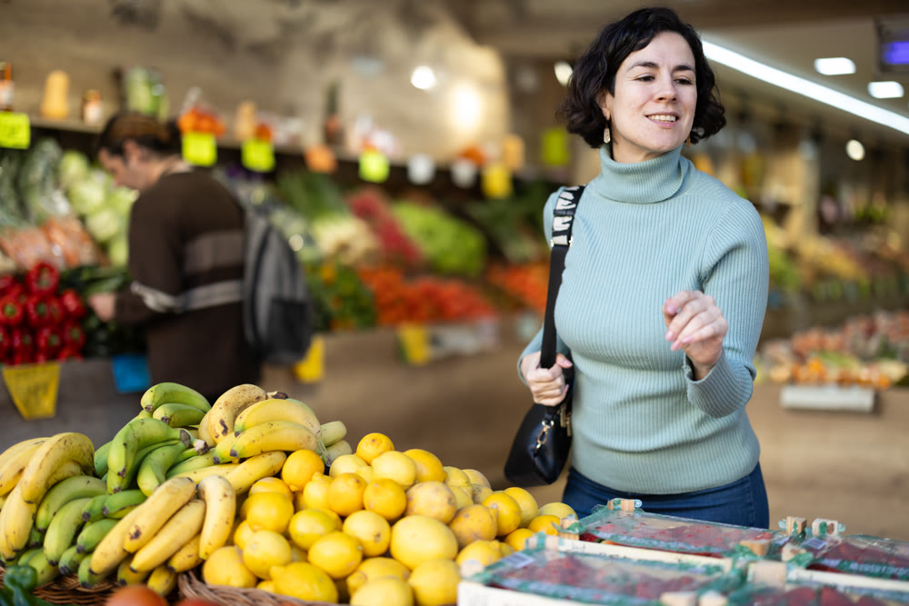 Adult woman choosing fruits and vegetables in vegetable shop