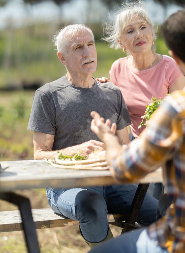 Happy family of farmers sits at table and discusses current affairs