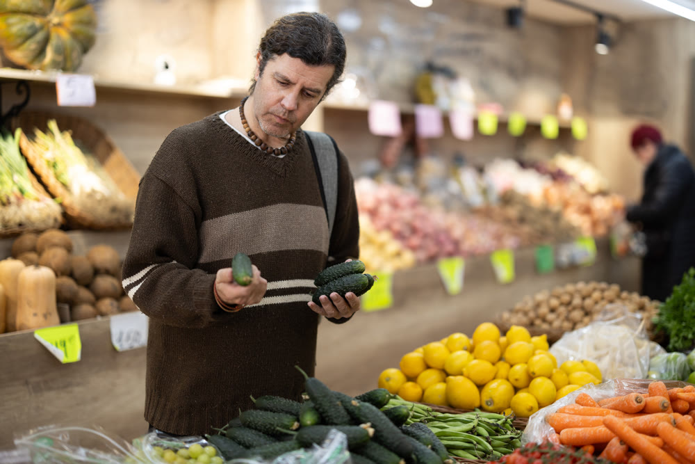Grocery shopping - male shopper choosing vegetables on supermarket counter