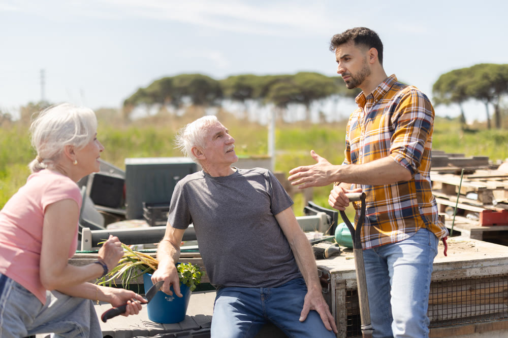 Mature couple and man argue with each other while standing near fence on small farm