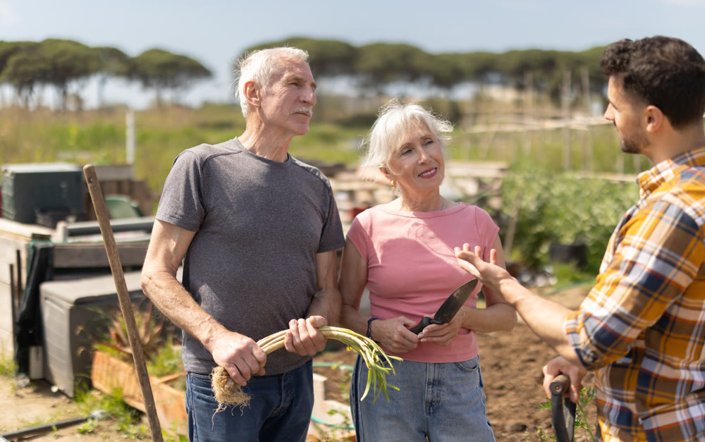 Elderly couple and young man talking together on farm field