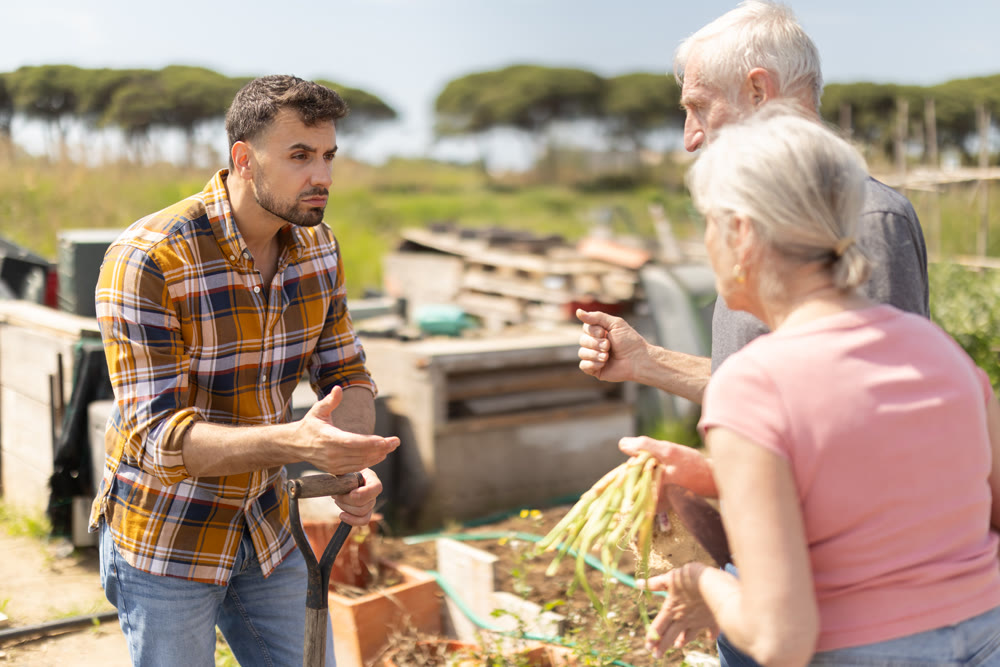 Mature couple and man argue with each other while standing near fence on small farm