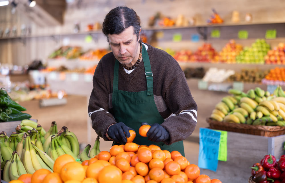 Adult man seller puts tangerines on display