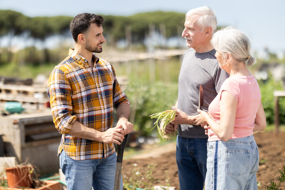 Elderly couple and young man talking together on farm field