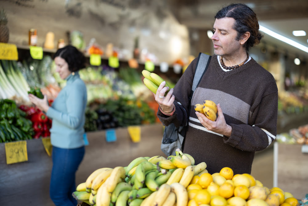 Man choosing bananas in supermarket