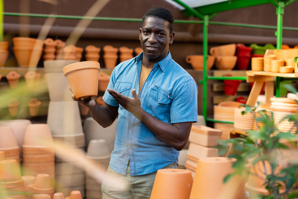 African american man choosing pots for flowers and trees in gardening market