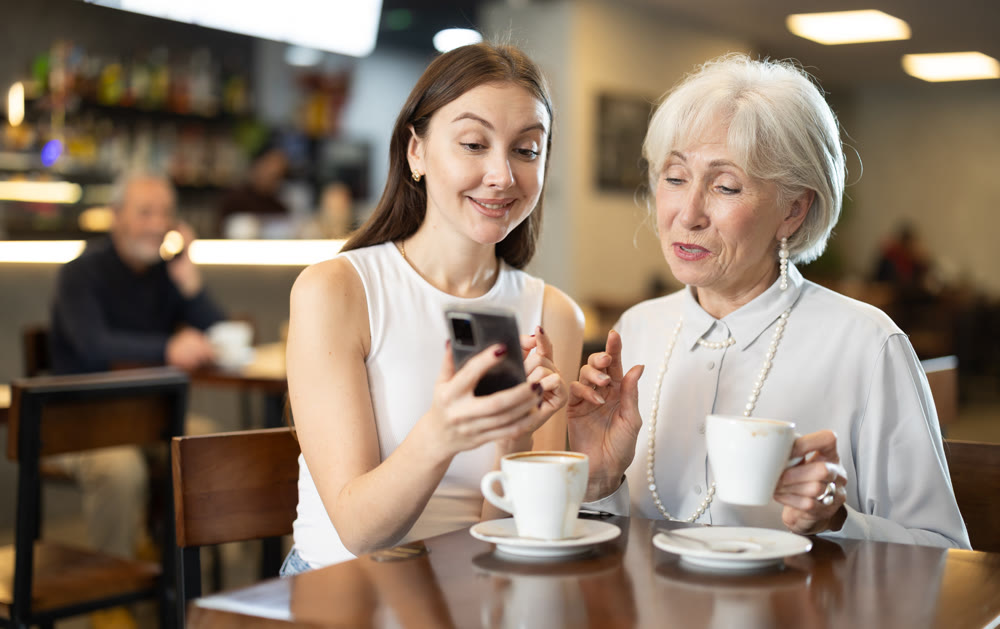 Young woman showing older woman photos on phone