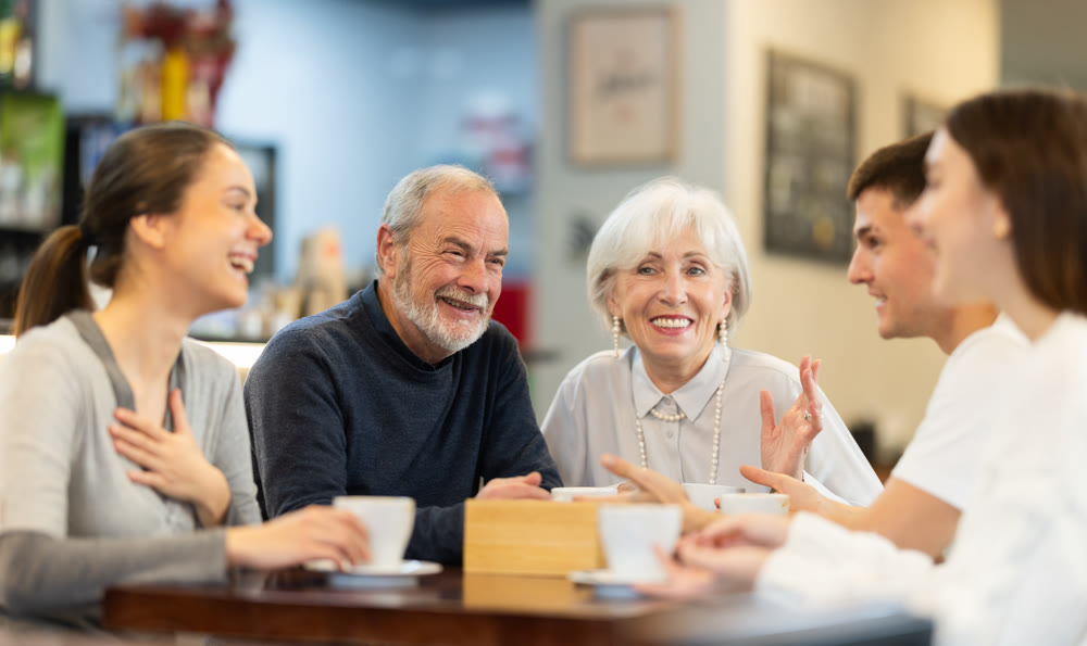 Young women and men talking to elderly people in a cafe