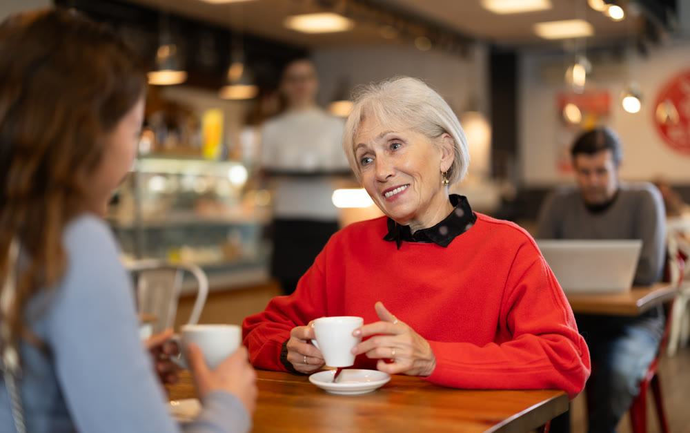 Elderly woman meets her adult daughter in cafe. Conversation over cup of coffee