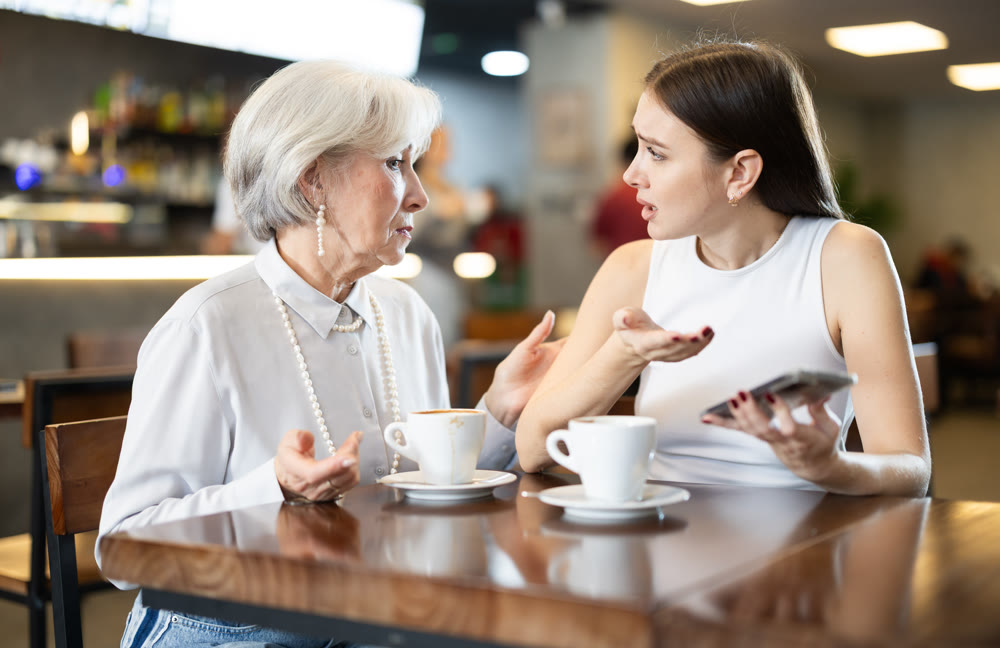 Elderly woman comforts young woman in cafe