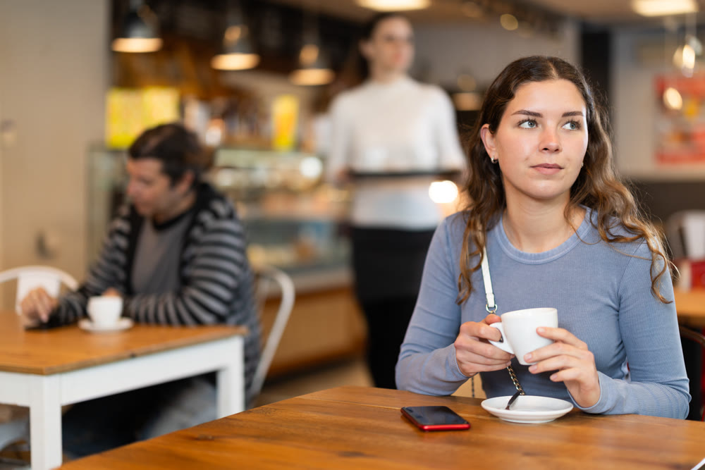 Portrait of girl with cup in hands drinking coffee in coffee shop indoors