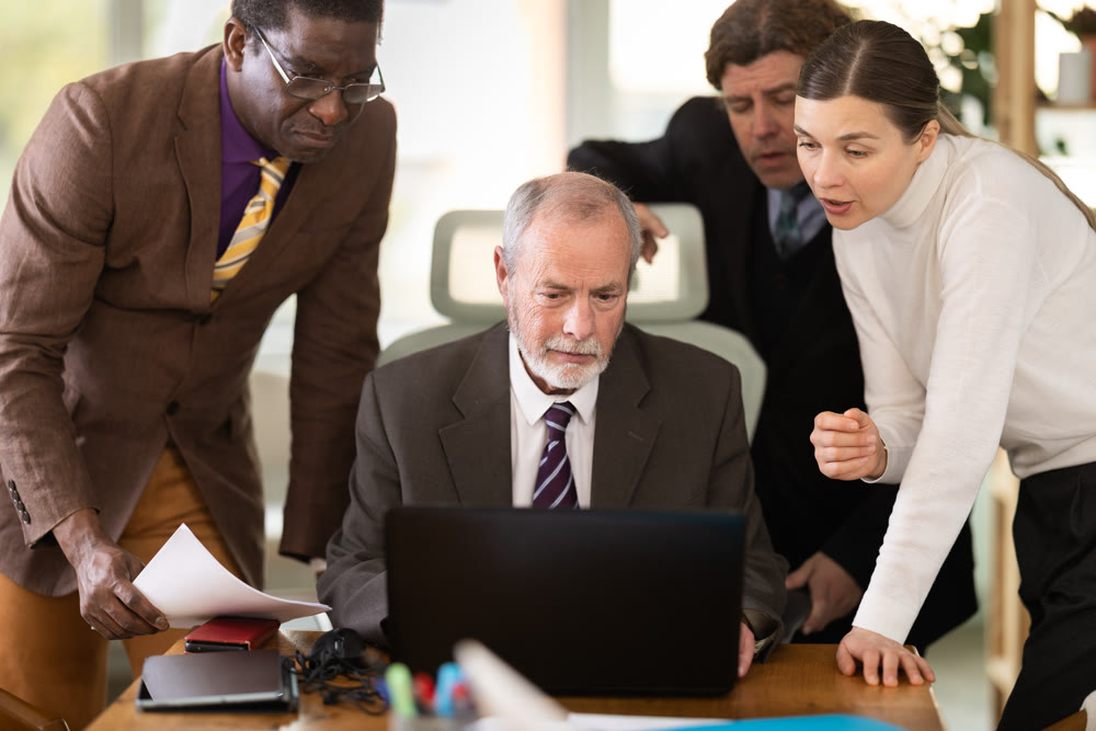Group of businessmen working together, looking at a laptop and discussing issues