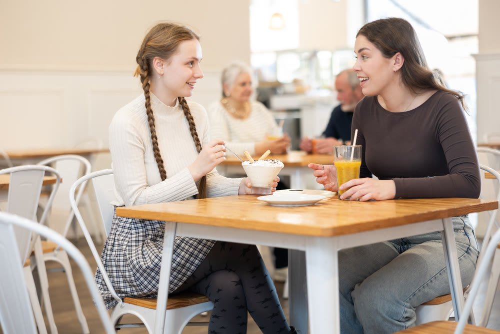 Young woman chatting with teenager in cafe