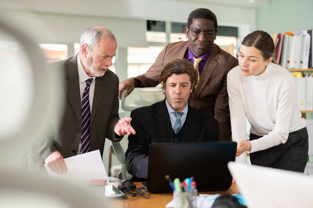 Group of businessmen in front of laptop screen, discussing business issues