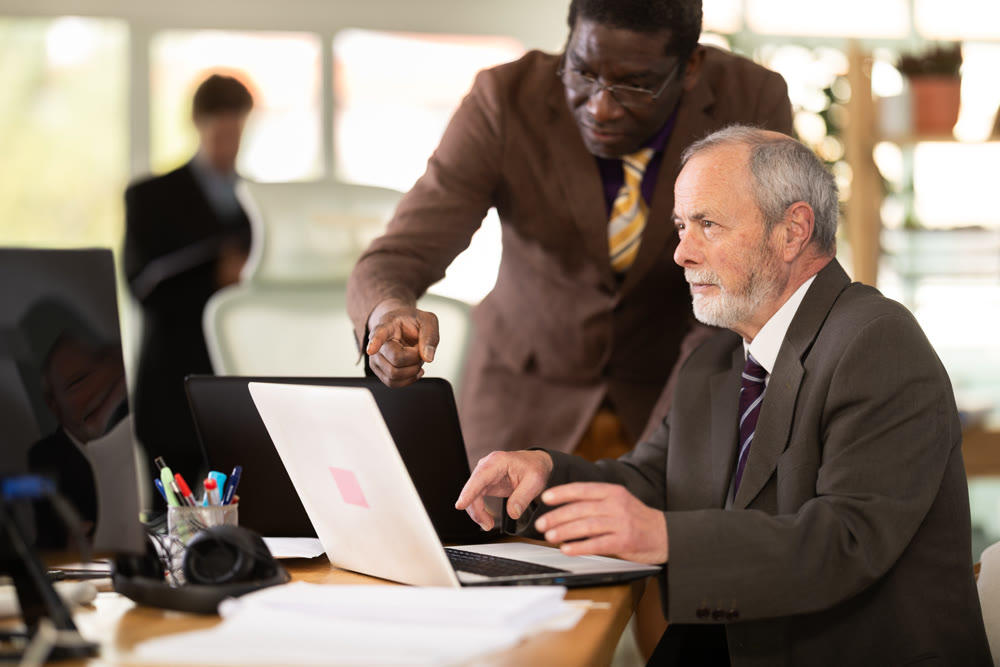 African businessman helps an employee with a program on a laptop