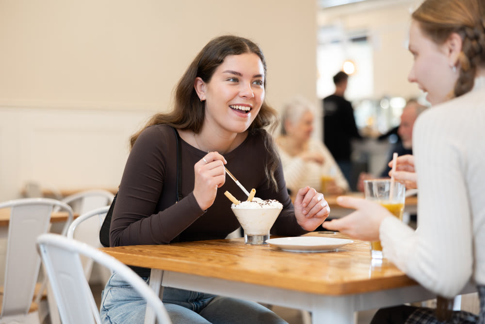 Young woman chatting with teenager in cafe