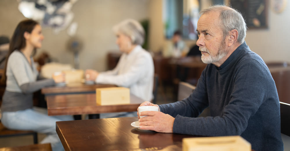 Elderly man with hot cup of coffee in hands