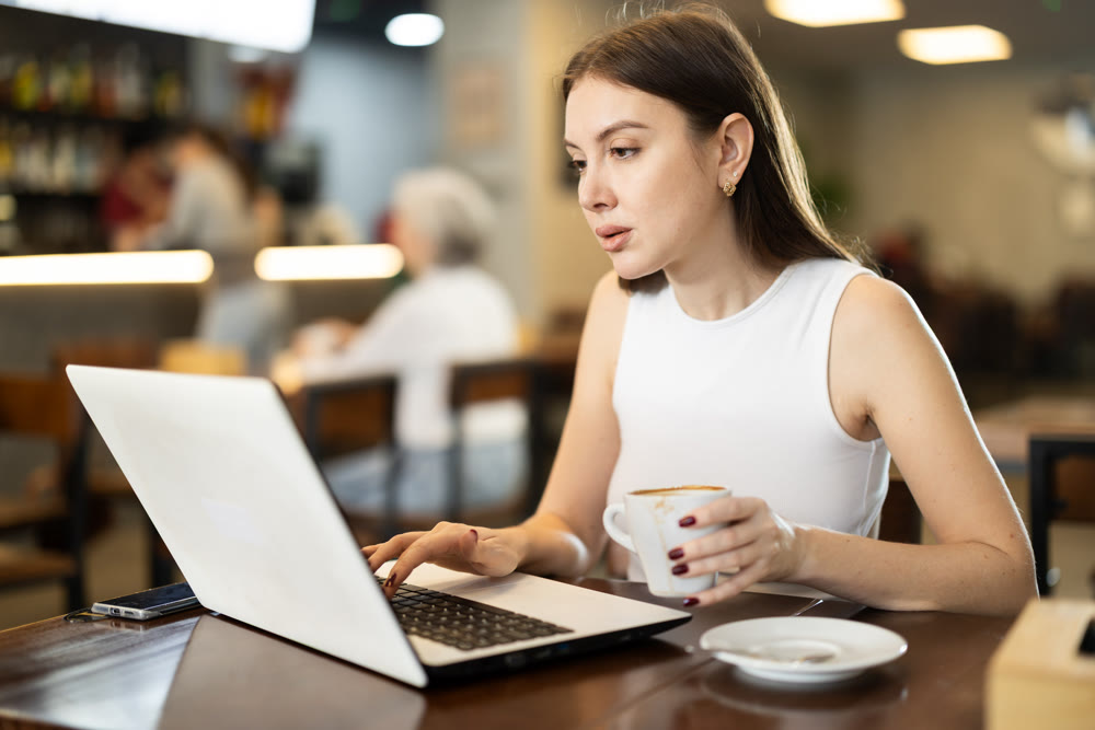 Young woman with laptop drinking coffee