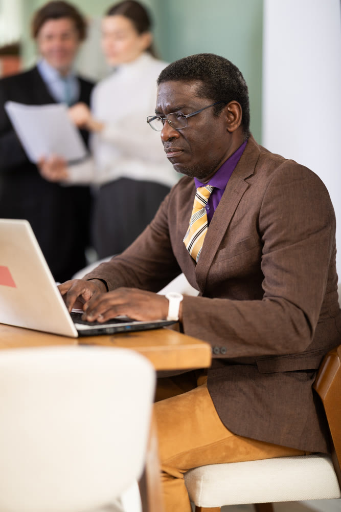 Confident man working online while checking reports of subordinates during a meeting in company office