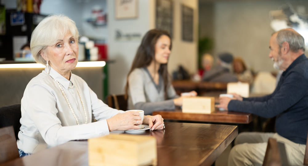 Senior woman whiles away time and drink coffee in cafe