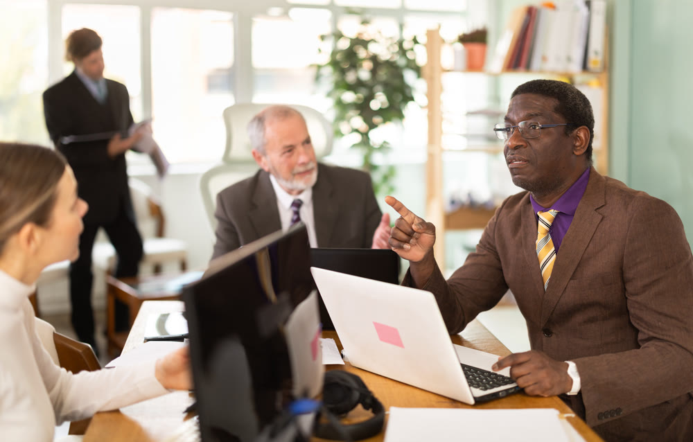 Businessmen use laptops during a conference in meeting room with colleagues