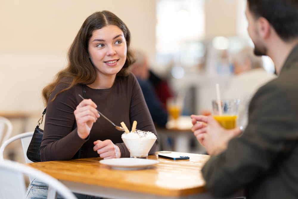 Young couple sitting in cafe and enjoying dessert with drinks