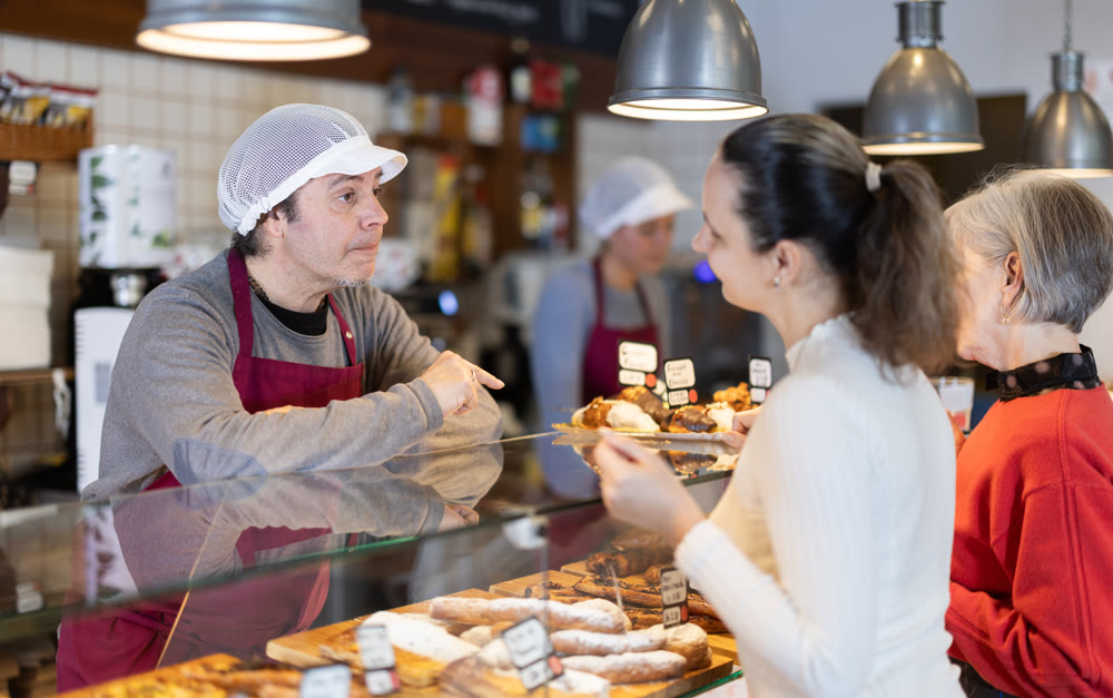 man coffee shop worker offers fresh pastries to customers