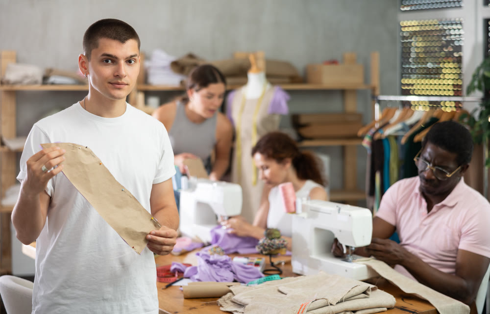 Young guy showing paper pattern in training sewing workshop