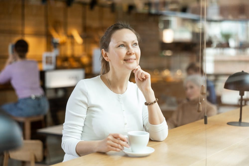 Relaxed woman sitting alone drinking coffee in quiet cafe