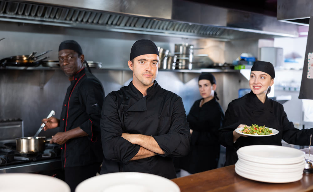 Portrait of confident chef with arms crossed in kitchen