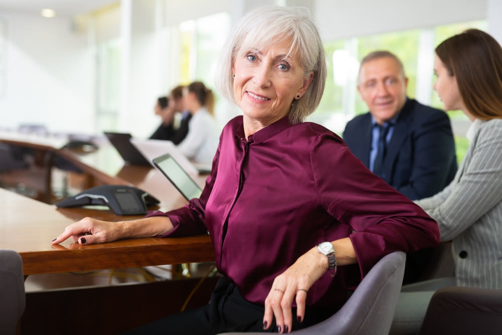 Elderly business woman using laptop at business meeting