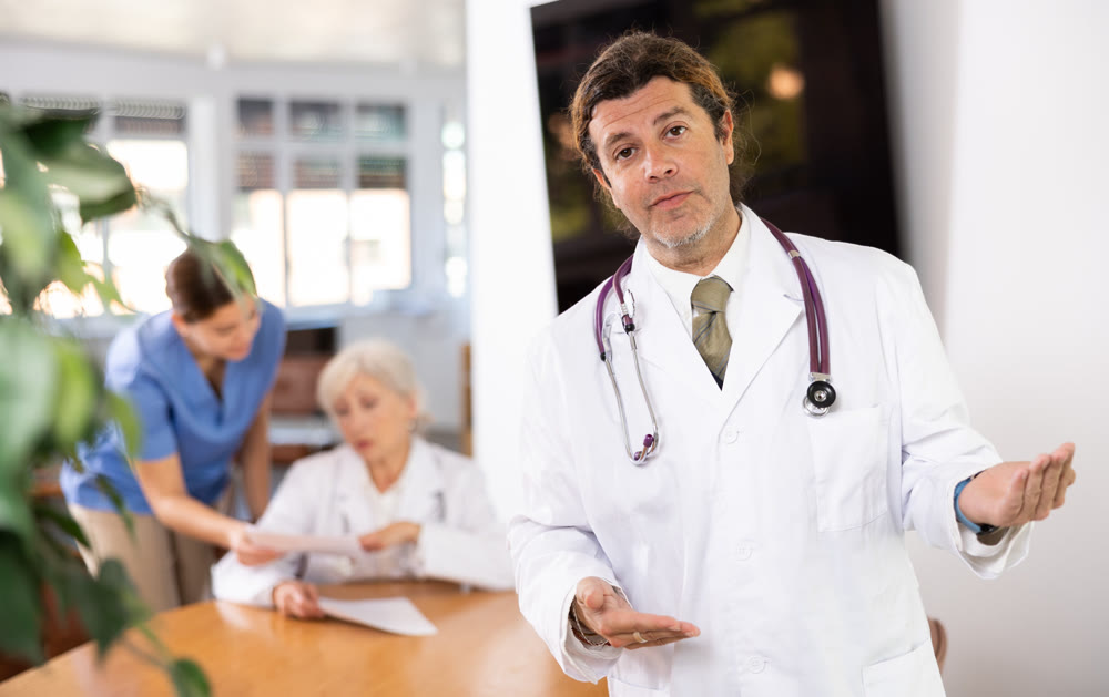 Professional doctor politely inviting patients in medical office