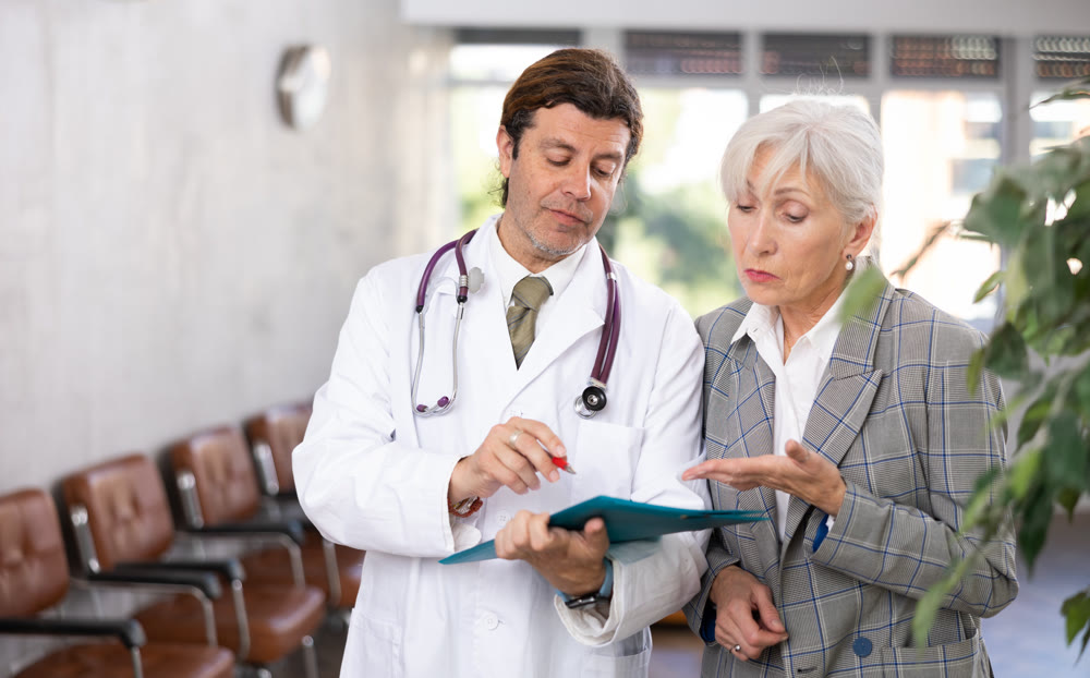 Adult male doctor and elderly woman with documents folder