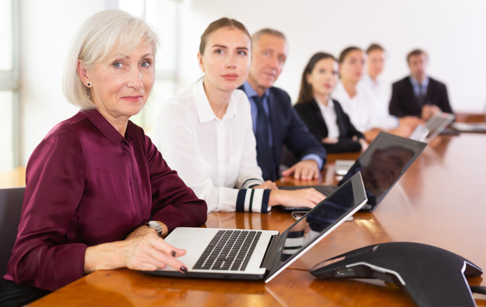 Elderly business woman using laptop at business meeting