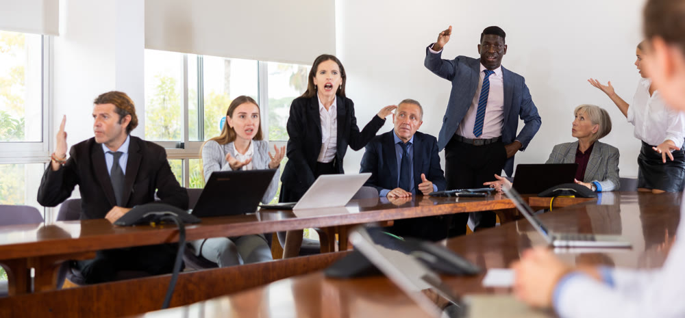 Managers expressing dissatisfaction with teamwork of colleagues at meeting