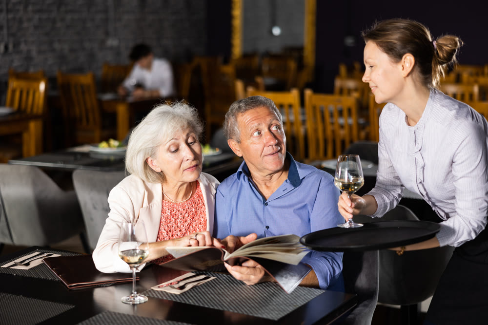 Woman waiter taking order from elderly couple in restaurant