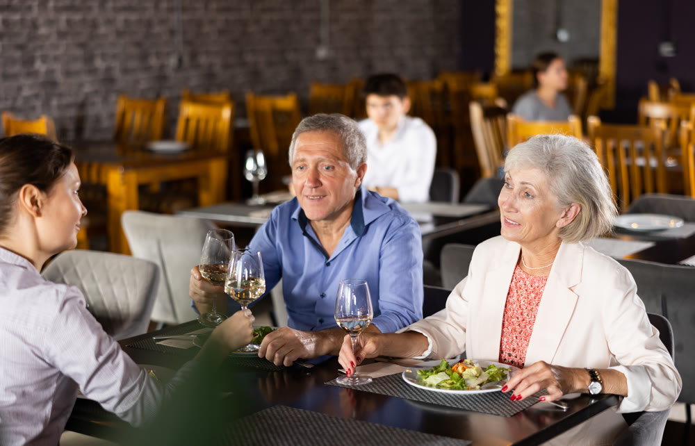 Elderly couple with adult woman having dinner in restaurant