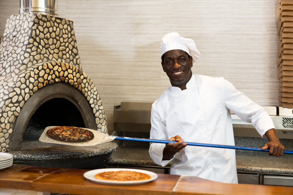 Emotional man chef preparing pizza in pizzeria