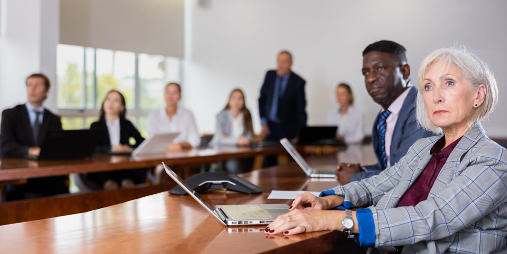 Mature senior white businesswoman listening to presentation