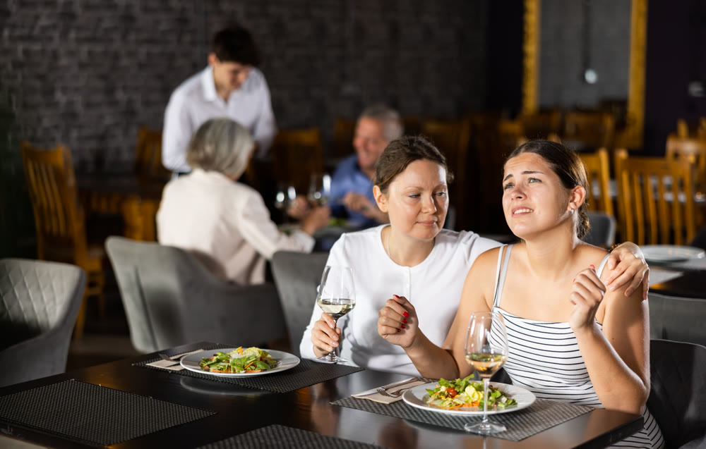 Young and adult women having dinner in restaurant