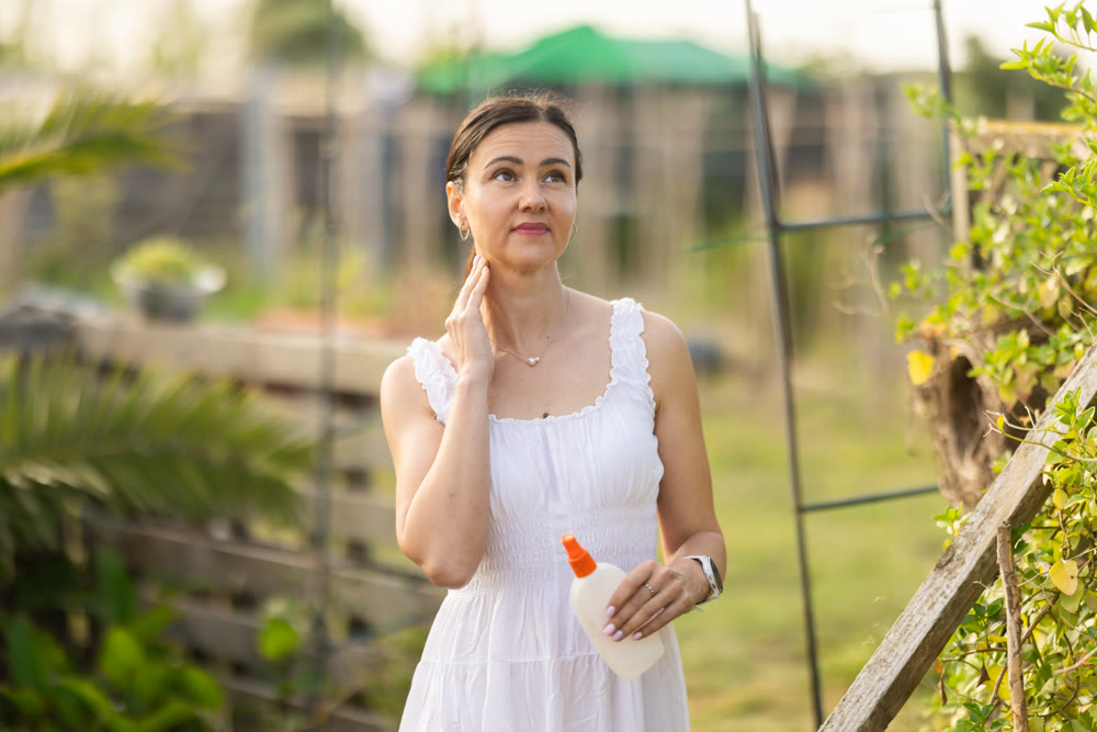 Adult woman applying repellent in cottage garden