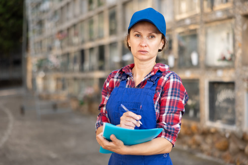 Female cemetery worker writing notes by columbarium