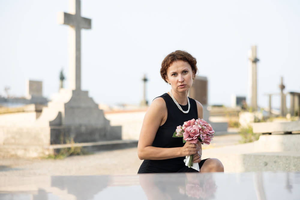 Woman brought flowers to the cemetery and cries over the death of beloved relative